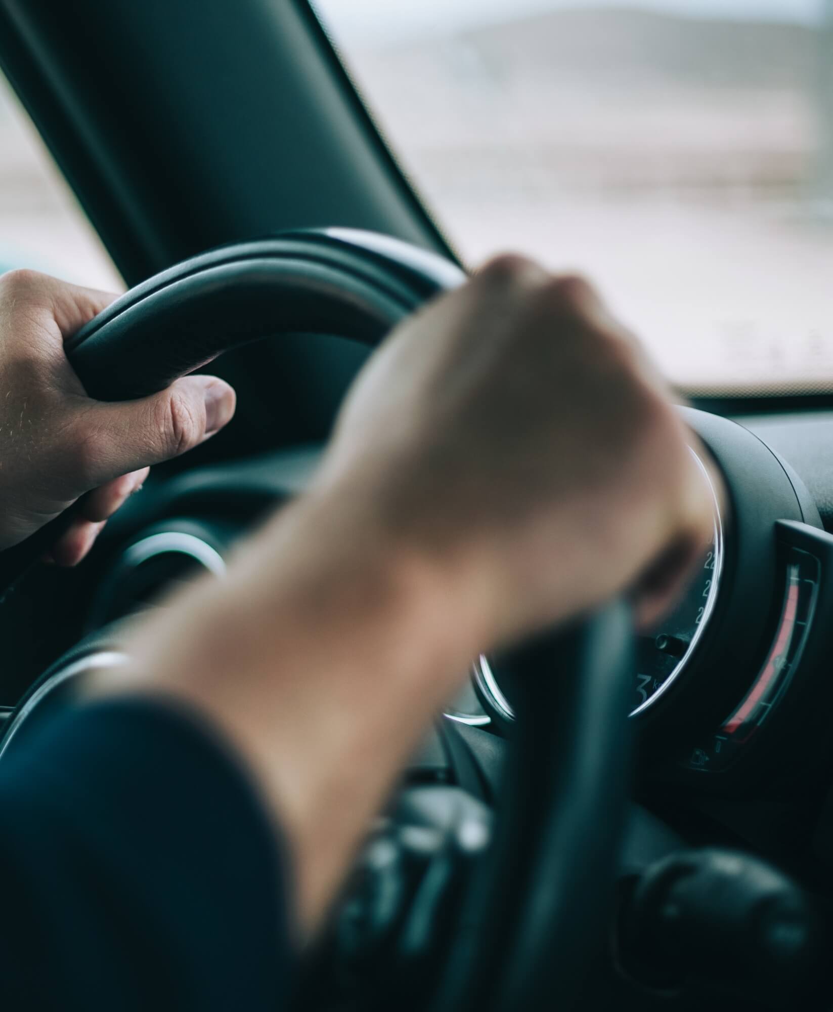 Innenansicht eines Autos mit zwei Händen am Lenkrad