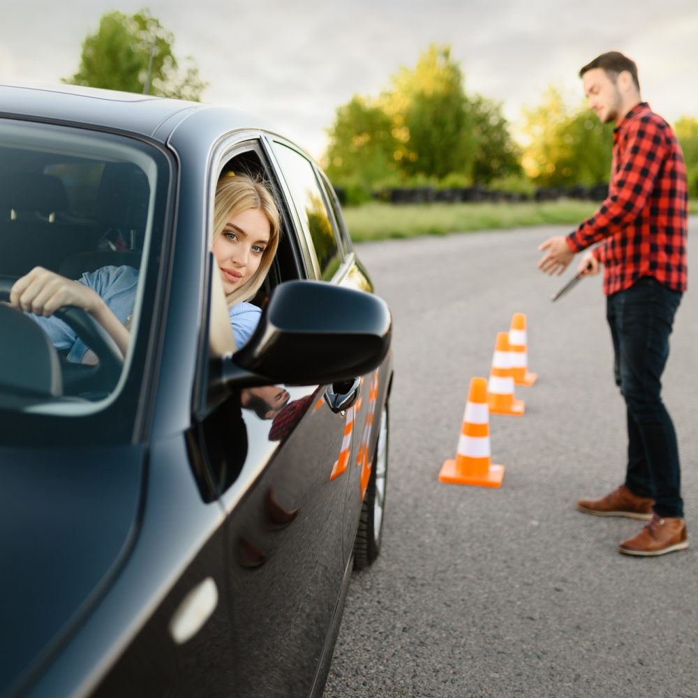 June Frau sitzt in einem schwarzen Auto und absolviert ein Fahrsicherheitstraining.